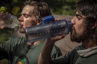 Image shows two Forest Service staff drinking water.