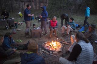 Image shows a group of people around a campfire.