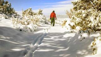 Person hikes through snow headed towards scenic overlook.