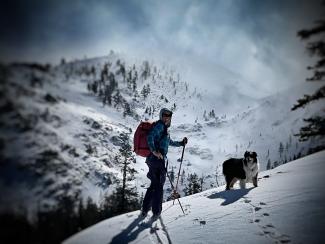 A person hiking with their dog on a snowy mountain