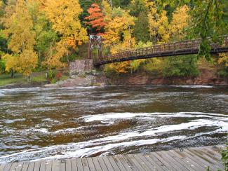 A bridge stretches over a wide river in fall.