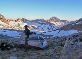 camper, tent, rocky terrain, mountains with snow