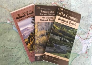 Three folded visitor maps of the ranger districts are fanned out.