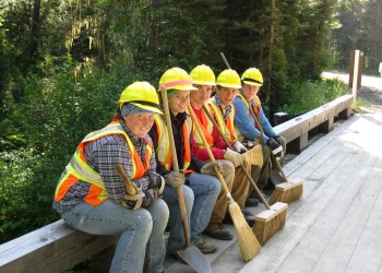 Volunteers sitting on a bridge rail with hard hats on