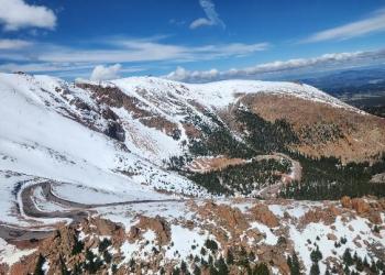 Helicopter view of the highway winding up a snowy mountain.