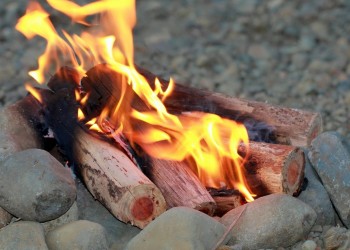 Yellow flames rise from a campfire with a rock fire ring.
