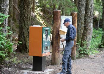Visitor paying at kiosk for parking permit at trailhead.