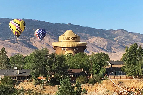 Smokey Bear balloon rising up over neighborhood homes