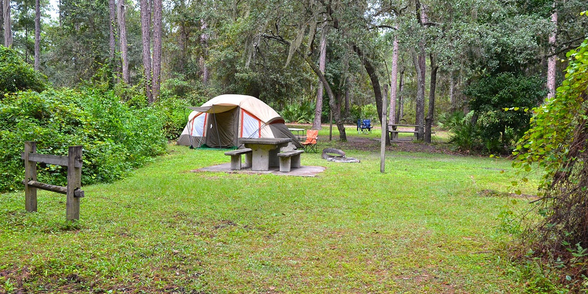 A campsite with a tent and several chairs.