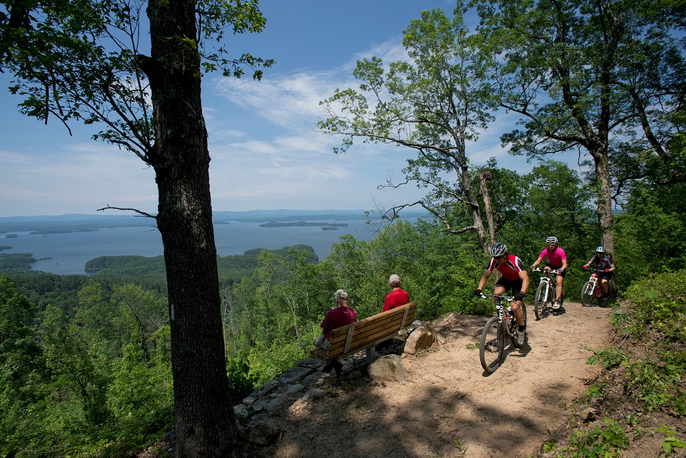 Hiker and mountain bikers on a scenic mountain trail overlooking a lake