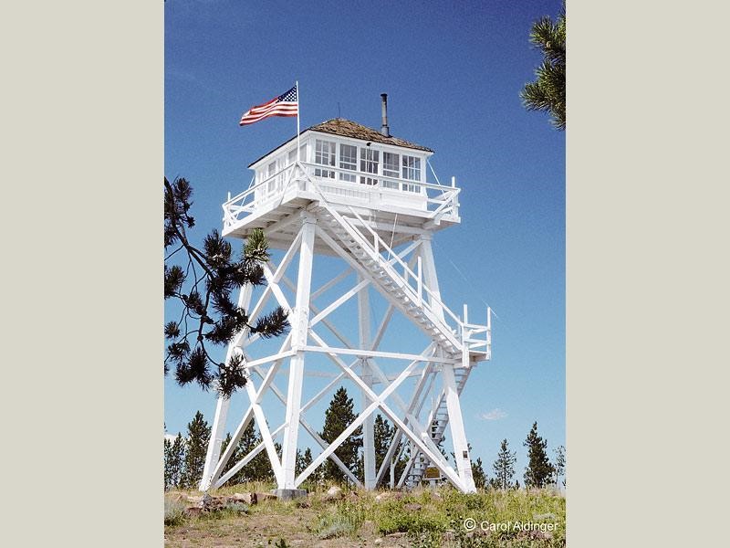 Photos of Ute Mountain Fire Lookout painted white with mountains and trees in the background.