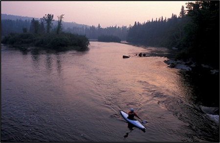 Kayaker paddling on the Androscoggin River at dusk