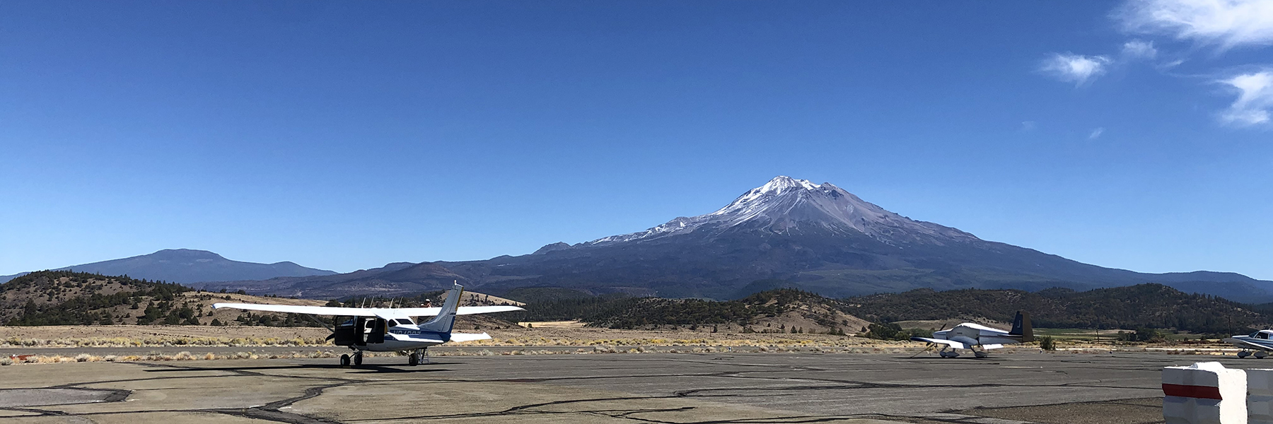 a plane sitting on the tarmac, snow capped mountain in the background