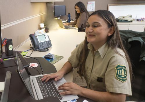 uniformed Forest Service employees working on a computer.