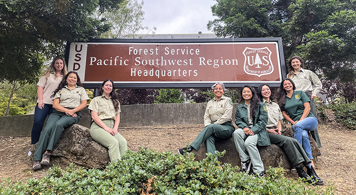 Group of eight people in front of sign saying “Forest Service, Pacific Southwest Region Headquarters.
