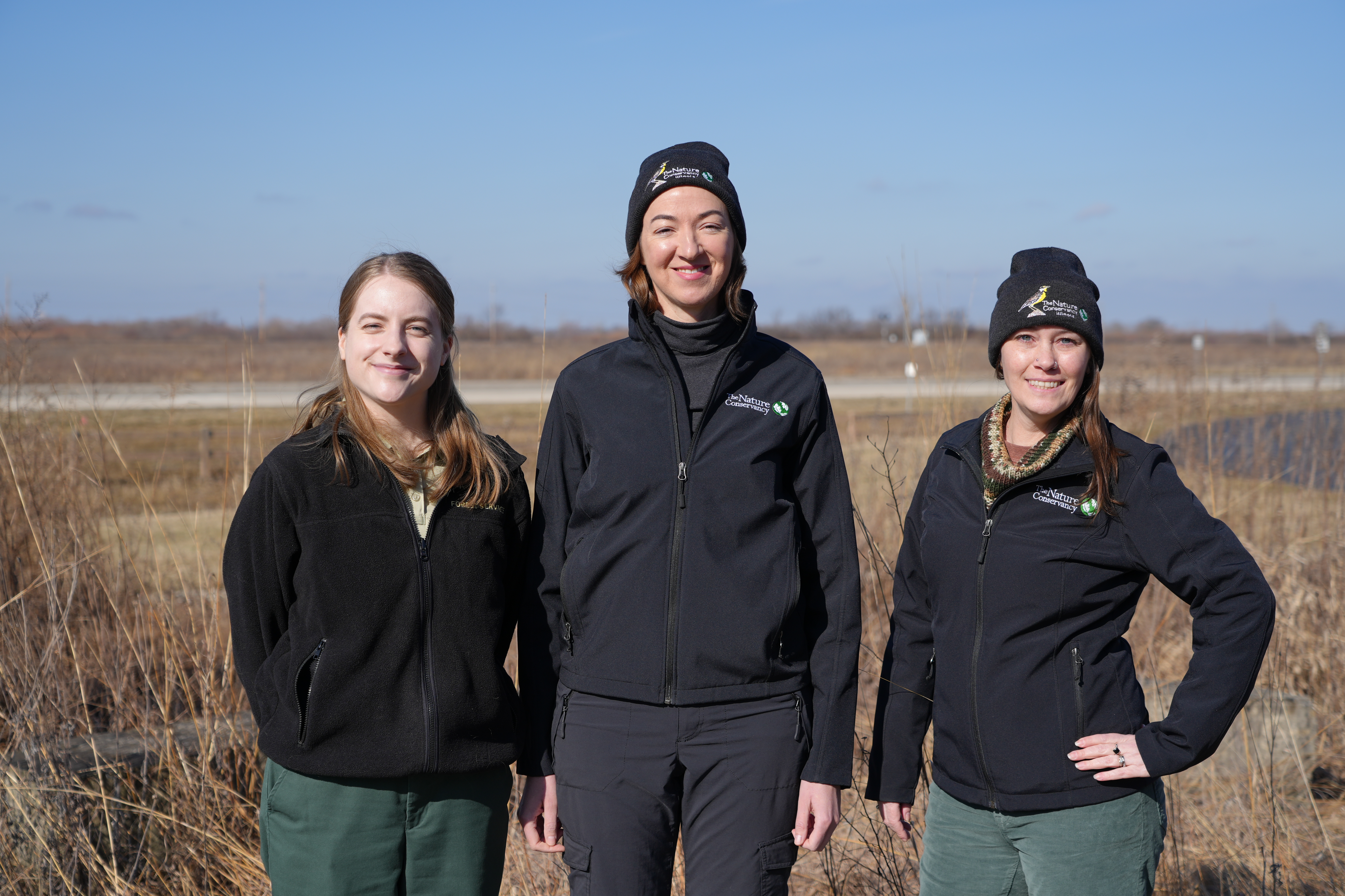 Photo of the three volunteer coordinators standing in a field