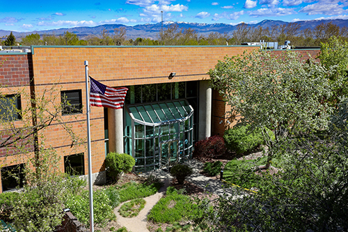 Aerial view of the building with an American flag waving with trees and mountains in background