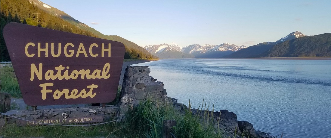 Chugach National Forest sign along the Seward Highway at Turnagain Arm looking south, mountains on the left, water on the right.