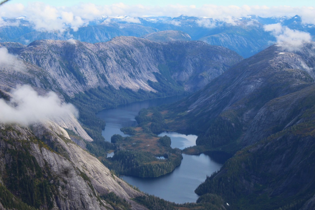 Aerial view of steep mountains, forest and water of Misty Fjords Wilderness.