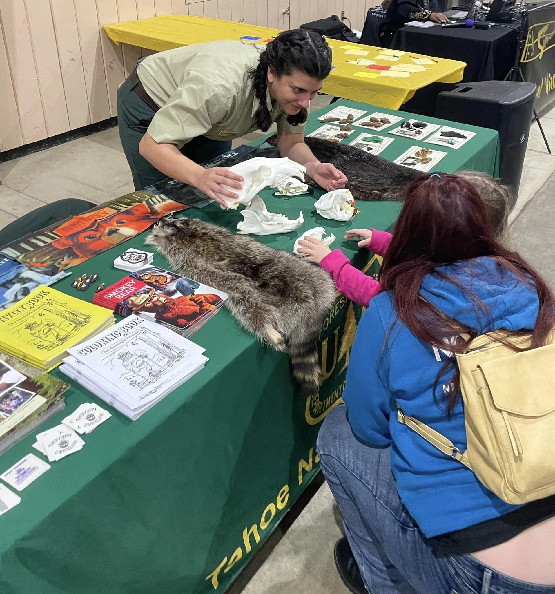 A person leans over a table to show a child some forest products.