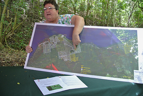 Marilyn Chakkroff in the field at a table, with a printed map pointing to the property in St. Croix.