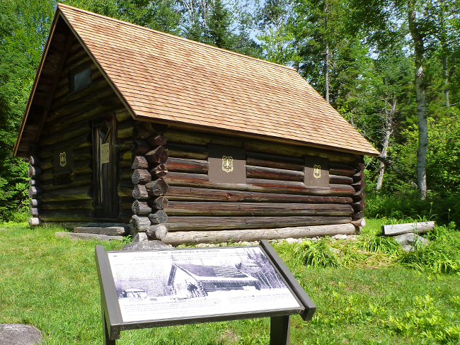 An interpretive panels sits in the foreground of a photo of the Fabyan Guard Station today.