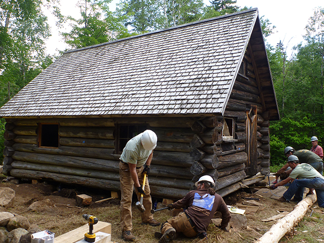 A team of volunteers work to restore the small cabin .
