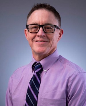 Image of a man in a purple shirt and tie