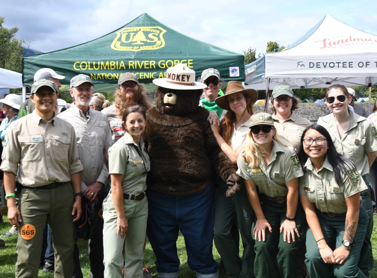 Rangers in uniform pose with Smokey Bear at a public event.