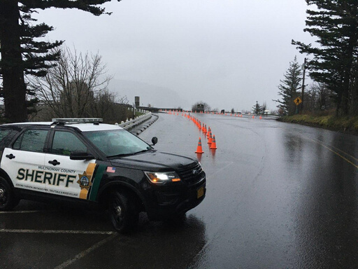 A police car and a line of orange cones on the historic highway marking a temporary closure.