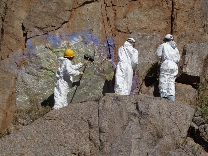 Workers scrubbing canyon wall to remove graffiti
