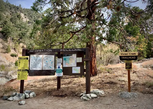 Image of the Vivian Creek Trailhead with trees, signs, rocks in the background