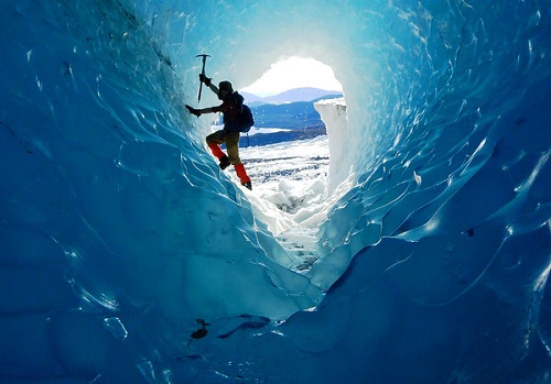 A person ice climbing in an ice cave.