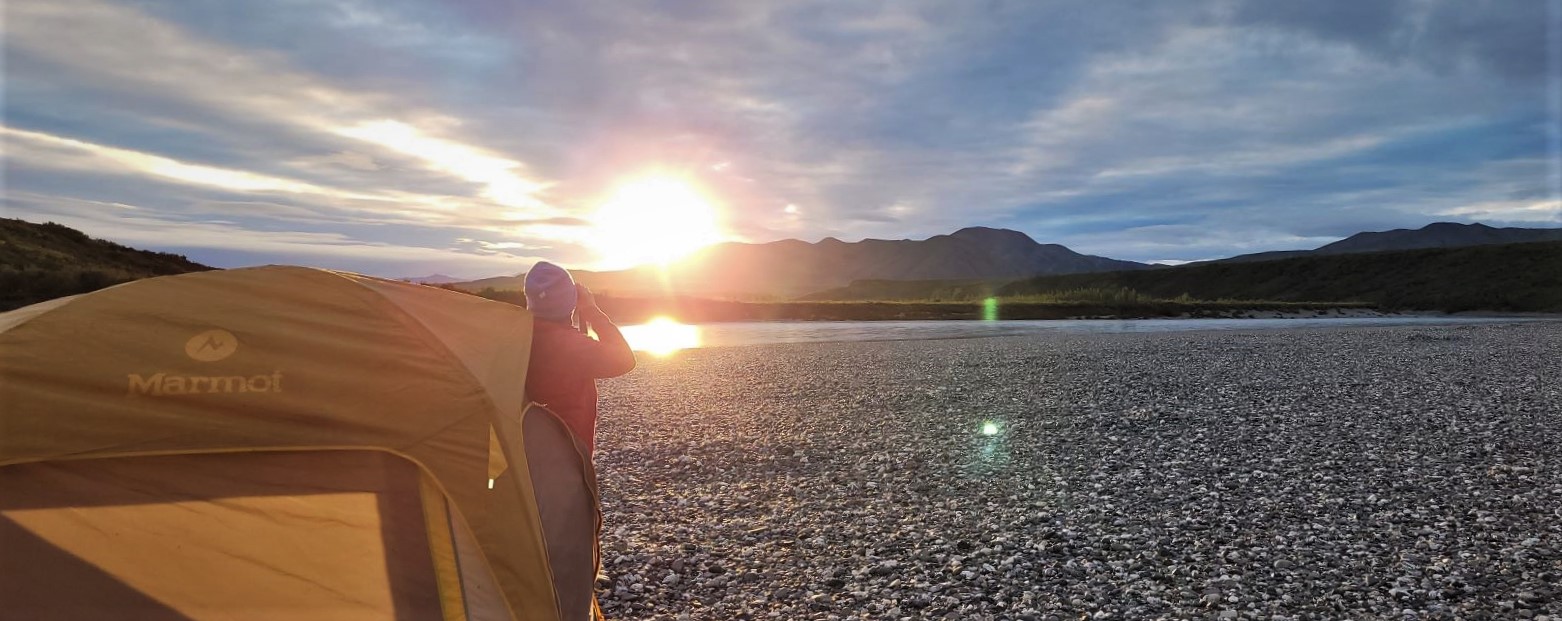 Claudia Ihl steps out of her tent to admire sunrise over the mountains.