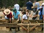 Crowds gather at wooden sluices to wash gravel in search of garnets
