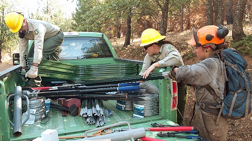 An SCA member helps unload fence sections from a Forest Service truck. 