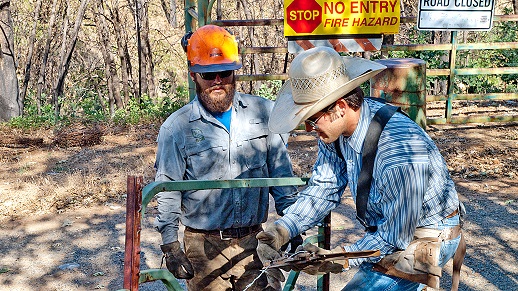 A local ranch hand explains fence replacement to an SCA member. 