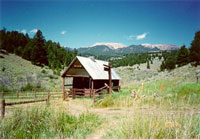 Photo of a wood cabin. Mountain and blue sky in the background
