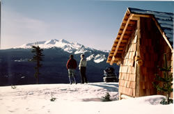 Fuji Shelter with skiers overlooking hill to snow covered mountains in background