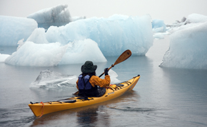 kayaker floating amidst icebergs