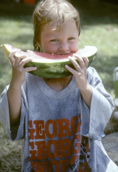 Child enjoying watermelon after a swim