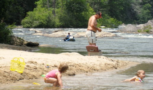 A father is seen fishing while his two little girls frolic in the water of the lower chattahoochee