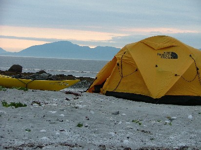 A kayak and tent sit on beach sand - a great durable surface.