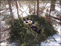 Forest Service employee laying down in a winter shelter during a trainng course