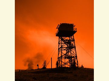 Silhouette of a lookout tower against a firey-colored background