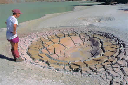 a person standing near a geyser opening in the ground