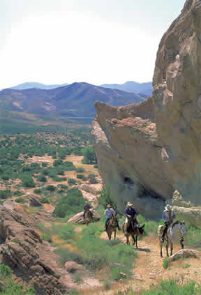 equestrians riding past large boulders in southern california