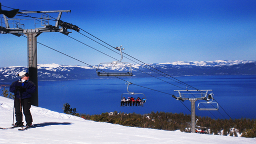 Color photo of ski lift with Lake Tahoe in the background.