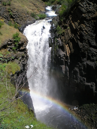 A rainbow graces the majestic Elk Creek Falls