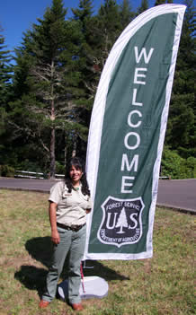 field ranger standing by tall Welcome Flag